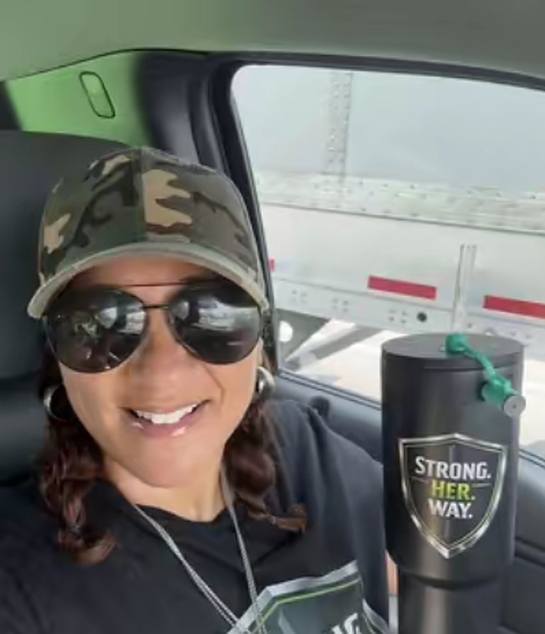 Tanya Robinson in a camo cap holding a Strong. Her. Way. tumbler