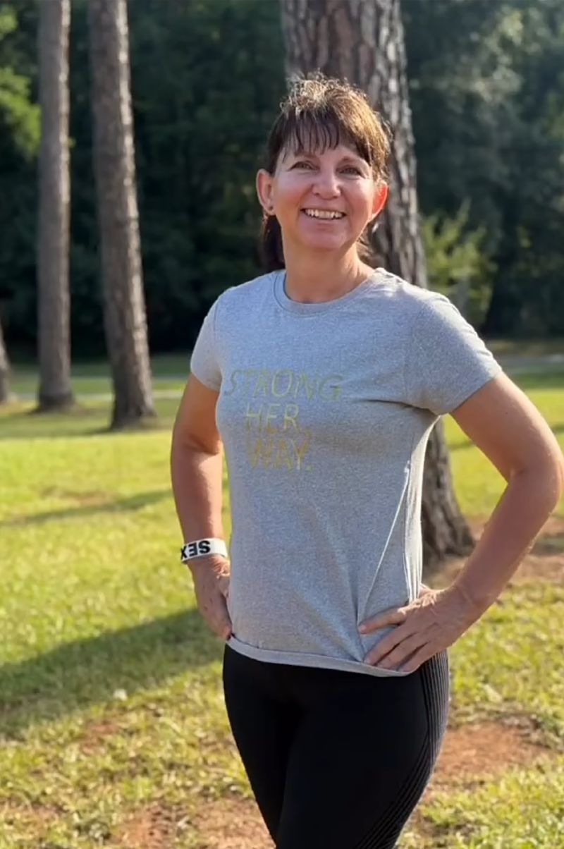 Member in a Strong. Her. Way. tee standing in the park